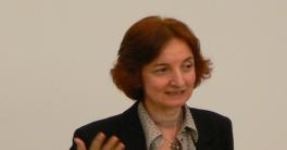 Former Director, Professor Yana Hashamova Woman with shorter red hair standing in front of a white background talking