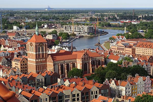Aerial view of city with red brick buildings with tile roofs, and a river in the background winding through the city
