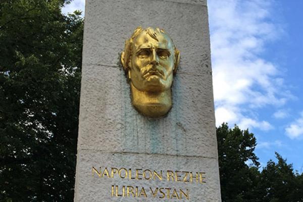 A stone pillar with a golden face and lettering on it